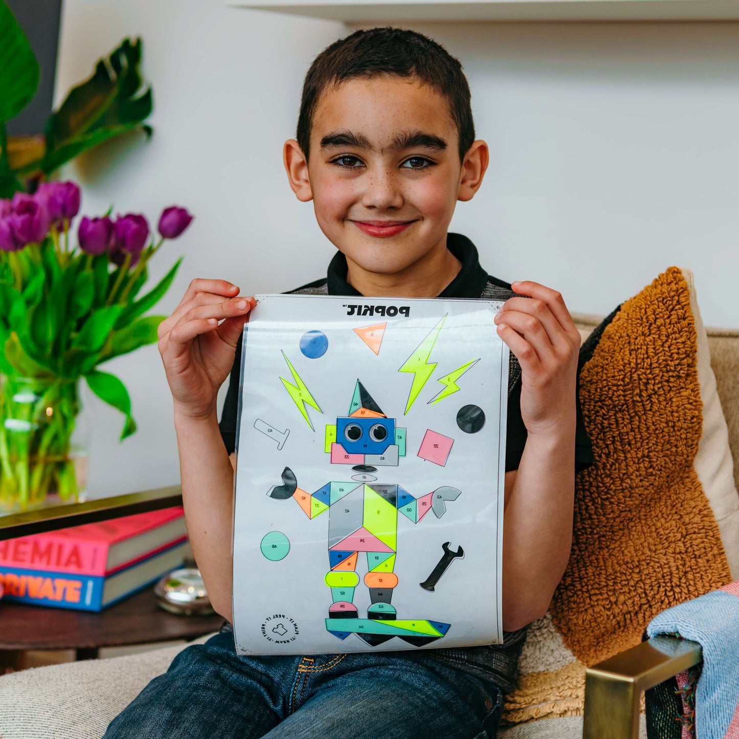 Smiling child holding a tote bag decorated with colorful craft prints